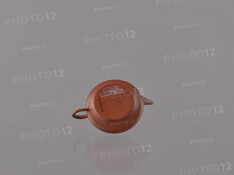 Teapot with lid; maker, Glezmer, Stanislaw 1853–1916 associated; Chinese; Qing dynasty 1644–1911; 19th century; Yixing-style red stoneware teapot; Yixing, Jiangsu, China; tea accessory vessel; height 4.0 cm, width 9.1 cm, A small reddish-brown rounded teapot viewed from above, showing its handle on one side and a short spout on the opposite side, resting on a smooth reflective gray surface that creates a faint reflection; the background is a uniform light gray.