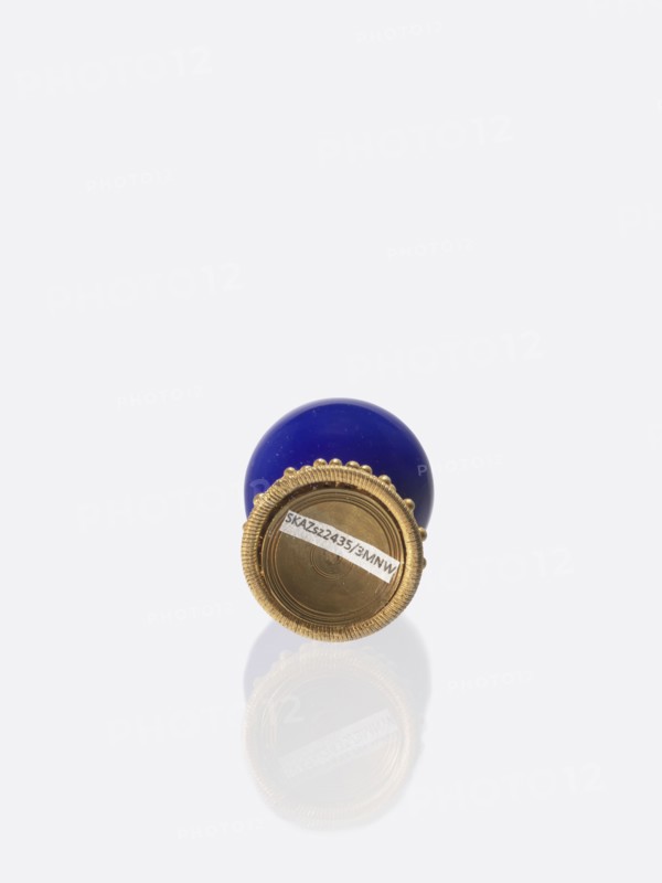 Button for a semi-official cap of a fourth-ranking official, Chinese, Qing 1644–1911, officials, emblems. Button composed of a blue-navy glass ball mounted on a pin with a dome decorated with rosettes. 19th century, China. Jewelry/clothing. Height 6.6 cm; diameter 3.1 cm., A round object with a glossy deep blue upper portion and a metallic gold lower portion, the gold area featuring a ridged decorative rim and a circular recessed center, all reflected faintly below on a white background; visible colors include blue, gold, white, and shades of gray.