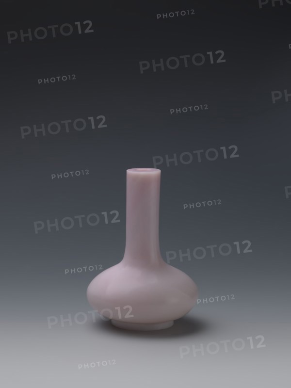 Vase, Chinese, Qing dynasty Qianlong, 1736–1795. Flask of pale pink glass on a low ring foot with a straight long cylindrical neck. 1736–1795. China. Vessel. Height 13.6 cm; diameter 9.8 cm; weight 0.35 kg., A small, rounded vase with a narrow, elongated neck and a bulbous base sits centered against a smooth gradient background; the vase is a pale pink color with subtle glossy reflections, and the background transitions from dark gray at the top to a lighter gray near the bottom, with a soft shadow beneath the vase.