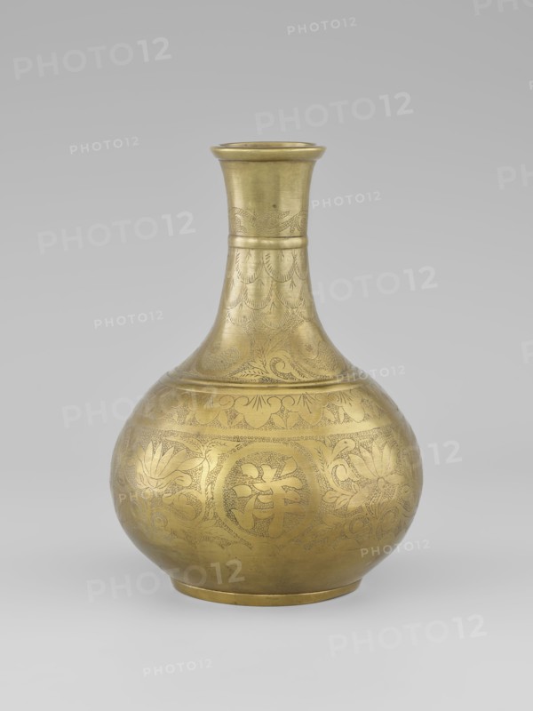 Vase — bottle;, ; Chinese art; Chinese; Qing dynasty 1644–1911; ornament: plant motifs, peonies; 19th century; China; vessel on a very low, ring-shaped foot; height 20.9 cm; diameter 15.38 cm., A brass-colored metal vase with a rounded body, a narrowing neck, and a flared rim, standing on a small circular base; the surface shows engraved decorative patterns including floral motifs, curved lines, and repeated scallop-like designs; the metal has a warm golden hue with areas of slightly darker patina and subtle shine; the background is a neutral light gray that fades evenly, and the vase casts a soft shadow on the pale surface beneath it.