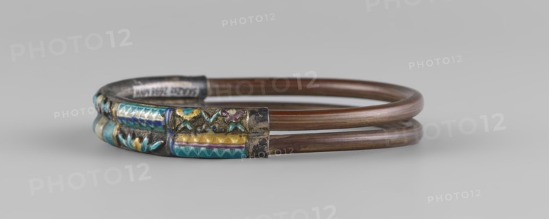 Bracelet, ornaments, Chinese art, Chinese culture, women's ornaments, Qing 1644–1911, plant ornament, enamel colors: white, yellow, teal, blue, 19th century, China, jewelry, diameter 7.0 cm, A double-loop bracelet composed of brown metal bands with a decorative metal section featuring inlaid enamel in turquoise, blue, yellow, purple, and green hues, set against a silvery base; the background is light gray.