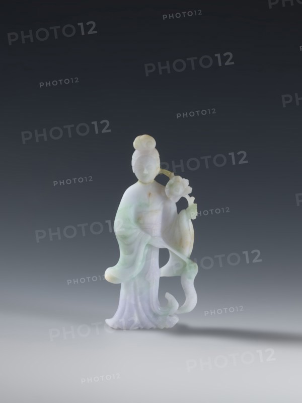 Taoist goddess?;, Chinese; Qing dynasty 1644–1911; Taoism; flowers iconography; scepter; green-pink slightly translucent jade; figurine sculpture; second half of the 18th century; height 17.1 cm, A carved figurine of a standing person made of pale stone with areas of green and lavender hues, wearing flowing robes with soft curves and folds, a rounded bun hairstyle, and holding a floral element near one shoulder; the surface shows smooth, translucent qualities and subtle color variations in white, light green, and pale purple against a neutral gray gradient background.