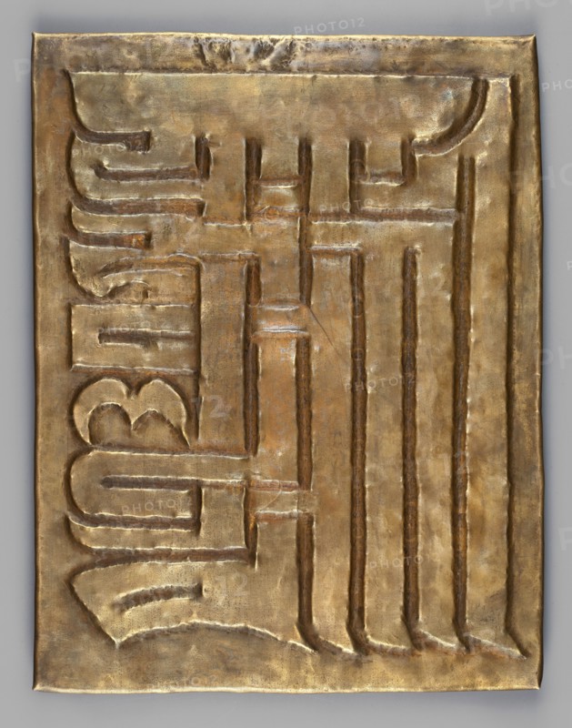 Garuda surrounded by other Buddhist deities; inscriptions; snakes; Kalachakra symbol. Sculpture plaque, height 34.6 cm, width 28 cm. Himalayan/Tibetan Buddhist art; 18th–19th century; possibly Tibet or Mongolia., A rectangular metallic panel with a raised, embossed surface showing an interlocking geometric pattern, rendered in shades of gold with areas of darker bronze and subtle greenish patina; the panel has a slightly irregular edge and visible small dents and creases, with the embossed channels forming rounded and straight grooves that create a repeating vertical and horizontal motif across the surface, and the overall appearance is metallic and reflective with warm golden, brown, and faint green tones.
