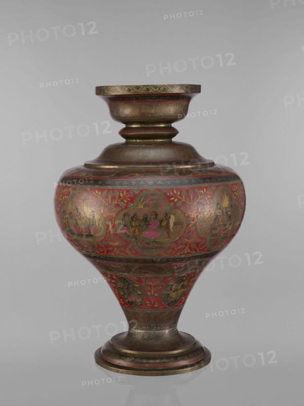 Vase, noted. Indian, 19th century. Vessel with a bulging, flattened belly tapering toward the bottom; wide spout and round foot. Polychrome in red, pink, yellow, white and black. Motifs include gods Vishnu, Shiva, teachers, fish, plant and geometric ornaments, ascetics; associated with Hinduism, Vaishnavism, Shaivism. Height 50.0 cm, diameter 13.0 cm, weight 5.75 kg., A rounded, ornate vessel with a flared rim and pedestal base sits against a plain background, showing a bulbous midsection that tapers to a narrow stem and circular foot; the surface features intricate decorative panels and floral motifs with a dominant red background and metallic areas that appear gold and bronze, along with accents of dark brown and small touches of pink and green, and the vessel displays a glossy finish with visible painted scenes and repeated patterned bands around the neck and base.