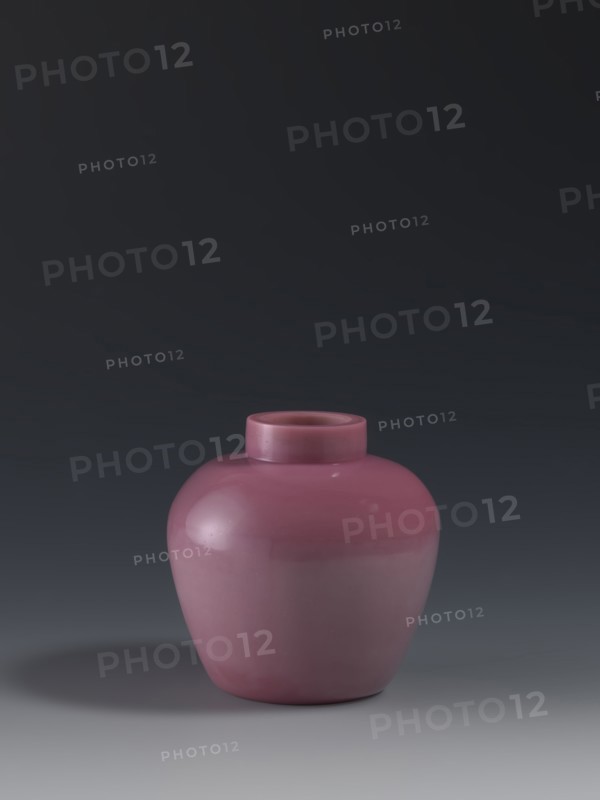 Ginger vessel, mid-19th century, China, Qing 1644–1911. Ovoid storage pot with a short collar. Porcelain vessel, height 11.5 cm, diameter 11.5 cm, weight 0.46 kg. Chinese art., A smooth rounded ceramic vase in a muted pink color sits centered on a flat surface, showing a short cylindrical neck and a glossy finish that reflects light; the background transitions from dark gray at the top to a lighter gray near the bottom, and there is a soft shadow in darker gray cast to one side.