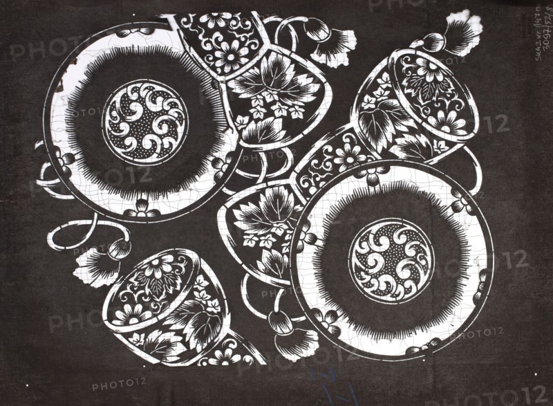 Dyeing stencil katagami with tsuzumi drum motif, ise-katagami stencil, chuban format, late 19th century Meiji period, Japan. Subject: tsuzumi drums and floral ornaments. Materials/technique: stencil katagami. Dimensions: height 40.6 cm, width 30.5 cm. /author., The image shows a high-contrast black-and-white composition of decorative round plates and teacups arranged overlapping each other, each featuring intricate floral and swirling motifs; the background is dark while the objects are primarily white with black detailing, and there are a few floral-shaped handles or embellishments extending from the ceramics.