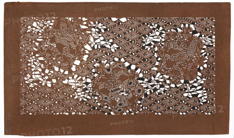Dyeing stencil katagami with a motif of rhomboidal flower rosettes and birds hanabishi ni tori moyô, ise-katagami, stencils, chuban format, kachoga iconography: birds, flowers, plum trees, hanabishi pattern, geometric and plant patterns. Pattern cut out on the pattern: against the background of a grid of flower rosettes enclosed in rhomboids, quadrilateral reserves with a pair of doves and a small plant motif., 19th/20th century Meiji period, Japan. Template; height 41.5 cm, width 24.3 cm., A rectangular sheet of brown paper with an intricate cutout pattern fills most of the image, showing a repeating floral-like lattice with many daisy-shaped motifs and organic, curving gaps; within this lattice are three ornate cartouche shapes each containing a stylized bird rendered by delicate cut lines and feather details; the cutwork reveals white background through the negative spaces, creating high contrast with the brown paper and occasional small areas of dark shadow where layers overlap, an...