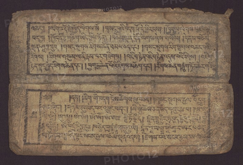 Buddhist text - Commentary on the praise of the names of Manjushri by Ga Rabjampa Kunga Yeshe Tib. 'phags pa 'jam dpal gyi mtshan yang dag par brjod pa zhugs so, unknown creator classification/graphic artist author; Buddhist art, Tibetan; graphic prints; Book in Tibetan pecha style; xylographic print in student script dbu can. 26 folios, recto page numbering, first verso, 2 pages missing. Buddhist commentary on the prayer of praise in honor of the names of the bodhisattva Manjushri Tib. 'jam dpal dbyang by Ga Rabjampa Kunga Yeshe Tib. sga rab 'byams pa kun dga' ye shes. Original text from the 15th century; object 19th century, Tibet. Graphics; width 24.6 cm, height 8.0 cm., An aged, rectangular object with a worn surface in shades of tan, beige, brown, and dark gray is shown against a dark background; it appears folded with an upper and lower panel separated by a narrow crease, each panel framed by a darker border and containing dense dark markings arranged in horizontal bands; the edg...