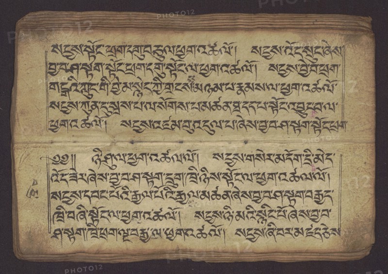 Buddhist Manuscript - Penitential Text Tib. sDig bshags gser gyi zhes bya ba bzhugs+o, unknown author/scribe-copyist, Tibetan Buddhist art, Himalayan culture, Book in Tibetan pecha style, manuscript in student's script. Leaf numbering 2-22 verso, first recto, last two unnumbered. Handwritten notes folio 24 recto and verso. 19th century, Tibet, manuscript, width 24.0 cm, height 8.1 cm, An aged, rectangular sheet with a textured, yellowed surface occupies the image, displaying dense, flowing dark ink strokes arranged in horizontal lines across the page; the ink appears black and contrasts with the warm beige and tan of the paper, which shows darker brown edges and slight discoloration spots; a horizontal fold or seam divides the sheet into upper and lower sections, and the top edge has a stack of layered pages visible with brownish tones; faint purple and pink blotches appear in small areas, and subtle greyish smudges and stains dot parts of the surface; thin, dark framing lines border s...