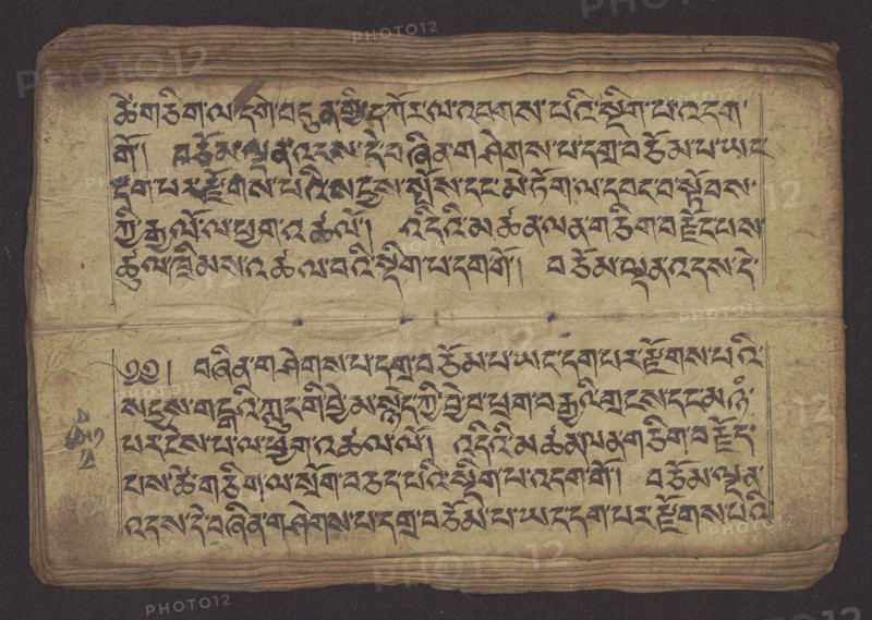 Buddhist Manuscript - Penitential Text Tib. sDig bshags gser gyi zhes bya ba bzhugs+o, unknown author/scribe, noted, Tibetan Buddhist art, Himalayan culture, Book in Tibetan pecha style, manuscript in student's script. Leaf numbering 2–22 verso, first recto, last two unnumbered. Handwritten notes folio 24 recto and verso. 19th century, Tibet, manuscript, width 24.0 cm, height 8.1 cm, An open aged manuscript page rests against a dark background, showing a worn beige paper with visible folds, creases, and a few small holes along the central horizontal fold; the page edges are layered and frayed with darker brown discoloration. The surface bears several lines of dense dark black calligraphic script arranged in two rectangular blocks separated by the central fold, with thin ruled borders around each block. The paper shows mottled stains and darker smudges, and there are subtle variations in the beige tone from pale to tan and light brown, along with the black ink of the writing and some fa...