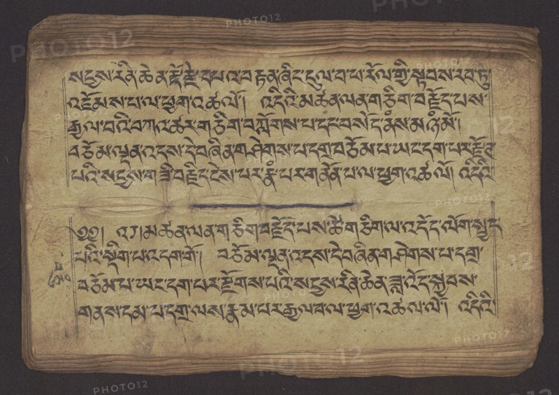 Buddhist Manuscript - Penitential Text Tib. sDig bshags gser gyi zhes bya ba bzhugs+o, unknown,  scribe-copyist author, Tibetan Buddhist art, Himalayan culture, Book in Tibetan pecha style, manuscript in student's script. Leaf numbering 2-22 verso, first recto, last two unnumbered. Handwritten notes folio 24 recto and verso., 19th century, Tibet type of place / place of origin, manuscript, width 24.0 cm, height 8.1 cm, A worn rectangular sheet with an off-white to yellowed surface and darker browned edges lies against a dark background; a group of dense black calligraphic lines covers much of the sheet in two separated blocks, with a thin horizontal dark stroke dividing them, and faint ruled margin lines framing the text areas; the paper shows creases, fold marks, small stains, and irregular darker smudges, and the sheet’s layered edges display a few visible stacked pages beneath.