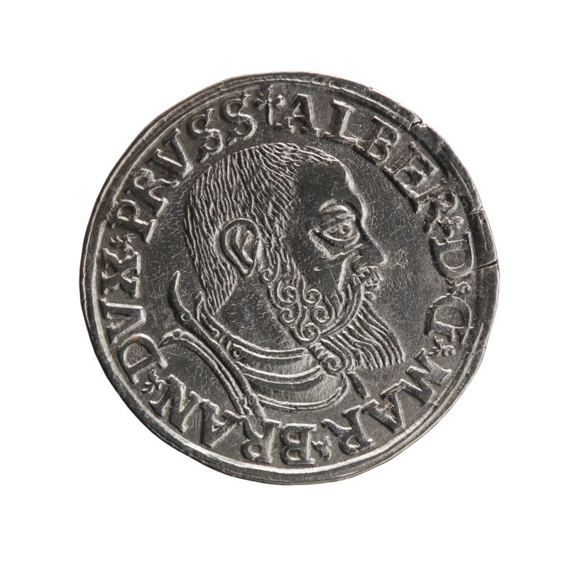 trojak, Vogelwaider Vogelwaid, Eustachius; publisher Decius, Jost Ludwik fl. 1528–1535 co-creator. Albrecht Hohenzollern Prince of Prussia; 1490–1568 — iconography: trefoils, male busts in armour. Obverse: male bust in armour in profile turned to the right; short hair, beard with sideburns. Inscription around the rim: *ALBER DG MAR BRAN DVX PRVSS*; continuous border, floral motifs between the words. Reverse: in the continuous border an inscription in six lines: -III-.GROSS:AR:/.TRIPLEX./.ALBER:DVC./.PRVSSIE./-I540- with the denomination and date between trefoil marks. 1540. Ducal Prussia 1525–1701, Königsberg mint. Coin; diameter 22.5 mm; weight 2.57 g; axis 45°., A circular metallic coin with a raised profile of a bearded man facing right, featuring detailed hair and beard texture and a decorative collar; the coin shows engraved edging and ornate border designs with worn surfaces and small dents. Visible colors include silver, gray, and subtle darker gray tones.