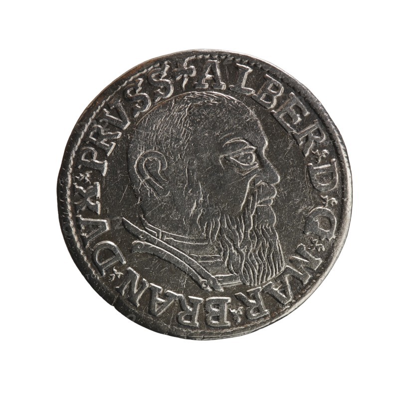 trojak, Schilling, Maciej mintmaster; Decjusz, Jost Ludwik fl. 1528-1535 co-creator; mint manager; Albrecht Hohenzollern Prince of Prussia; 1490–1568 — iconography: trefoils, male busts in armour. Obv.: male bust in armour in profile turned right; short hair, long beard with sideburns; rim inscription beginning with a trefoil: -ALBER D G MAR BRAN DVX PRVSS; pearl border; plant motifs between words. Rev.: pearl border with six-line inscription: -III-.GROSS:AR:/.TRIPLEX./.ALBER:DVC./.PRVSSIE./-I54I- denomination and date between trefoil marks. 1541, Königsberg; Ducal Prussia 1525–1701. Coin; diameter 22.7 mm; weight 2.43 g; axis 45°., A circular metallic object with a worn silver-gray surface showing a raised profile of a bearded man facing right, with textured hair and beard details and facial features in relief; a raised rim around the edge and a decorative band of raised elements encircling the portrait; overall colors include silver-gray with darker gray shadows and slight brownish t...