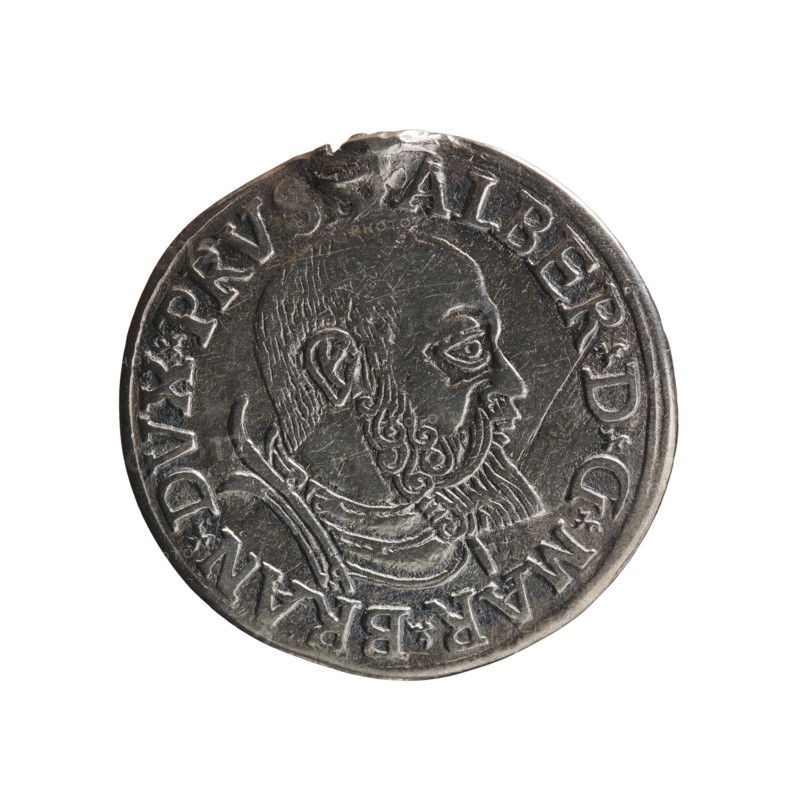 trojak, Schilling, Maciej mintmaster; Decjusz, Jost Ludwik fl. 1528-1535 co-creator; mint manager. Albrecht Hohenzollern Prince of Prussia; 1490-1568 — iconography. Obv.: male bust in armour in profile turned to the right; short hair, beard with sideburns. In the rim an inscription beginning with a trefoil: -ALBER DG MAR BRAN DVX PRVSS; double continuous border, plant motifs between the words. Rev.: in a double continuous border an inscription in six lines: -III-.GROSS:AR:/.TRIPLEX./.ALBER:DVC./.PRVSSIE./-I54I-. The denomination and date are between the trefoil marks. 1541. Ducal Prussia 1525–1701, Königsberg mint. Coin; diameter 22.5 mm; weight 2.44 g; axis 220°., A round metallic coin with a raised profile of a bearded man facing right, showing detailed hair and beard texture, an ear, and a stylized collar; the coin surface is silver-gray with darker tarnished areas and lighter highlights; there is a raised decorative rim around the edge and a ring of raised characters encircling the...