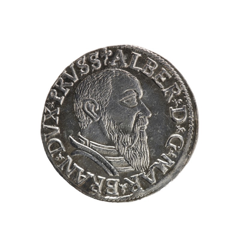 trojak; Straub Strawb, Heinrich mintmaster / publisher; Decjusz, Jost Ludwik fl. 1528–1535 mint manager / co-creator; Albrecht Hohenzollern Prince of Prussia; 1490–1568 — iconography: male busts in armour, trefoils. Obverse: male bust in armour in profile turned to the right; short hair, long beard with sideburns. In the rim an inscription beginning with a trefoil: -ALBER DG MAR BRAN DVX PRVSS; pearl border, floral motifs between the words. Reverse: in the pearl border an inscription in six lines: -III-.GROSS:AR:/.TRIPLEX./.ALBER:DVC./.PRVSSIE./-I54Z-; the denomination and date are between the trefoil marks. 1542. Ducal Prussia 1525–1701, Königsberg mint. Coin; diameter 21.2 mm; weight 2.71 g; axis 30°., A round metallic coin with a raised profile of a bearded man facing right, showing textured hair and a long beard; the man wears a layered collar or garment with carved lines. The coin surface is silver-gray with darker gray recessed areas and highlights on raised edges. There is a rai...