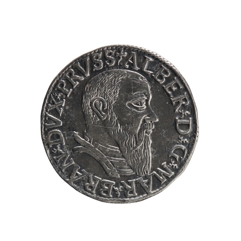 trojak; Straub Strawb, Heinrich mintmaster/publisher; Decjusz, Jost Ludwik fl. 1528–1535 mint manager/co-creator. Albrecht Hohenzollern Prince of Prussia; 1490–1568 — iconography: male busts in armour, trefoils. Obverse: male bust in armour in profile facing right; short hair, long beard with sideburns. In the rim an inscription beginning with a trefoil: -ALBER DG MAR BRAN DVX PRVSS, pearl border, plant motifs between the words. Reverse: in the pearl border an inscription in six lines: -III-.GROSS:AR:/.TRIPLEX./.ALBER:DVC./.PRVSSIE./-1542- denomination and date between trefoil marks. 1542. Ducal Prussia 1525–1701. Coin; diameter 21.3 mm; weight 2.56 g; axis 315°., A round metallic object with a raised profile of a bearded man facing right, showing a short hairline, detailed ear, prominent eye, and a long pointed beard, set against a flat background and surrounded by a raised border with decorative characters; the metal appears dark silver to gray with lighter highlights on the raised a...