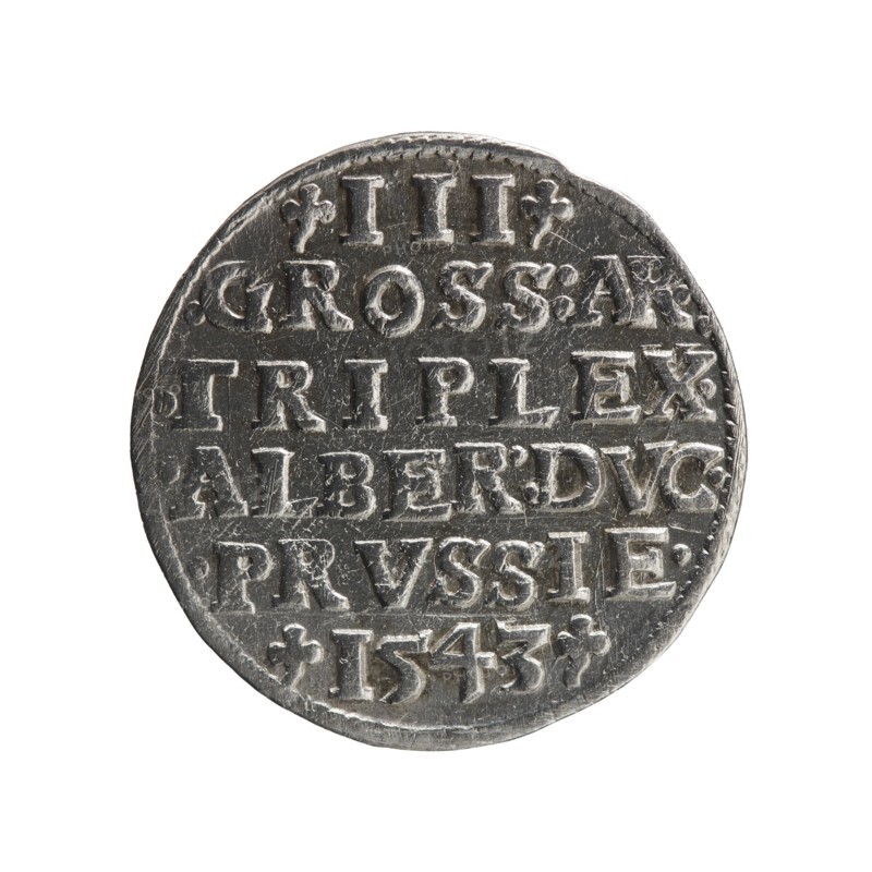 Trojak by Schilling, Maciej mintmaster and co-creator Decjusz, Jost Ludwik fl. 1528–1535, mint manager. Obverse: male bust in armour in profile facing right; short hair, long beard with sideburns; rim inscription beginning with a trefoil: -ALBER DG MAR BRAN DVX PRVS; pearl border, plant motifs between words. Reverse: six-line inscription in the pearl border: -III-/.GROSS:AR:/.TRIPLEX./.ALBER:DVC./.PRVSSIE./-I543-; denomination and date between trefoil marks. Dated 1543, Ducal Prussia 1525–1701, Königsberg mint. Coin; diameter 21.2 mm, weight 2.55 g, axis 170°., A round metallic object with a worn surface and a raised rim, showing engraved and embossed markings across its face; the object appears in shades of gray and silver with darker recessed areas and lighter highlights on raised details, and the background is white.