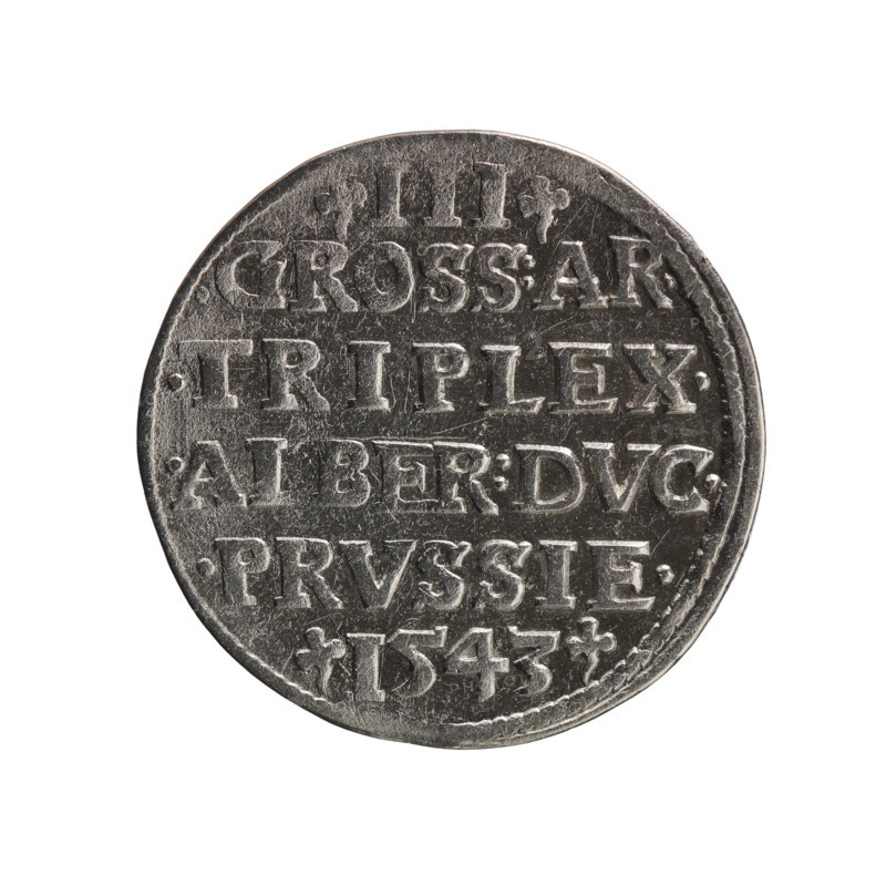 trojak, Schilling, Maciej mintmaster publisher, Decjusz, Jost Ludwik fl. 1528-1535 mint manager co-creator; Albrecht Hohenzollern Prince of Prussia; 1490-1568 — iconography: trefoils, male busts in armour. Obv.: male bust in armour in profile turned to the right; short hair, long beard with sideburns. In the rim an inscription beginning with a trefoil -ALBER DG MAR BRAN DVX PRVS; pearl border, plant motifs between the words. Rev.: in the pearl border an inscription in six lines -III-/.GROSS:AR:/.TRIPLEX./.ALBER:DVC./.PRVSSIE./-I543-; denomination and date between trefoil marks. 1543, Königsberg; Ducal Prussia 1525–1701. Coin, diameter 21.7 mm, weight 2.48 g, axis 225°., A round metallic coin shown against a white background with a worn surface and raised decorative elements across its face; the coin appears silver-gray with darker gray shadows in engraved areas and lighter gray highlights on raised edges, and it has an irregular slightly scalloped rim.