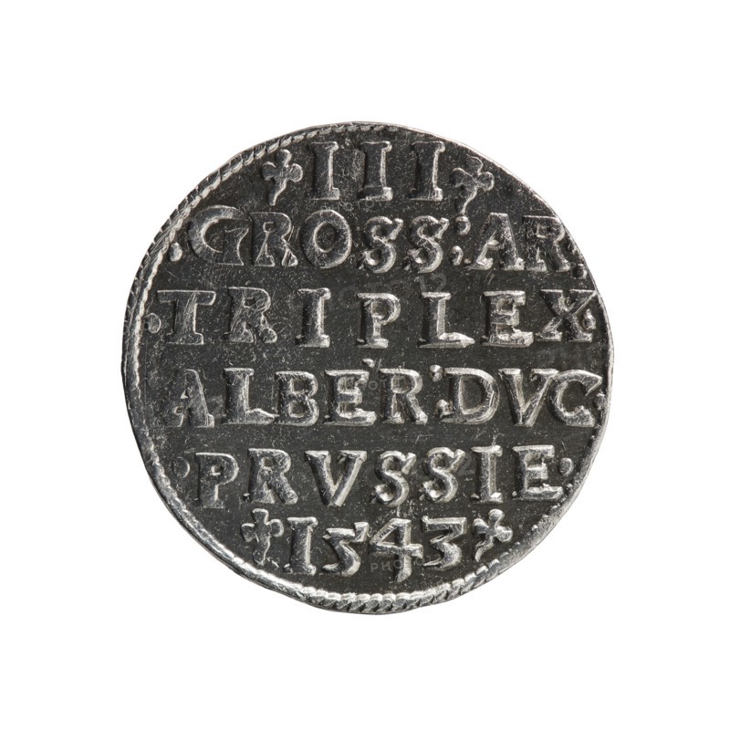 Trojak by Schilling, Maciej mintmaster, co-created with Jost Ludwik Decjusz fl. 1528–1535. Obverse: male bust in armour in profile facing right; short hair, long beard with sideburns; rim inscription beginning with a trefoil: -ALBER DG MAR BRAN DVX PRVSS pearl border, plant motifs between words. Reverse: pearl border with six-line inscription: -III-/.GROSS:AR:/.TRIPLEX./.ALBER:DVC./.PRVSSIE./-1543- denomination and date between trefoil marks. 1543. Ducal Prussia 1525–1701, Königsberg mint. Coin; diameter 20.8 mm, weight 2.57 g, axis 200°., A round metallic object with a textured rim, showing a worn dark gray and silver surface and raised shapes arranged in horizontal rows; the raised shapes form blocky, carved letter-like forms and small decorative elements; the object appears slightly irregular at the edge and displays areas of brighter silver where the raised surfaces catch light against darker recessed areas.