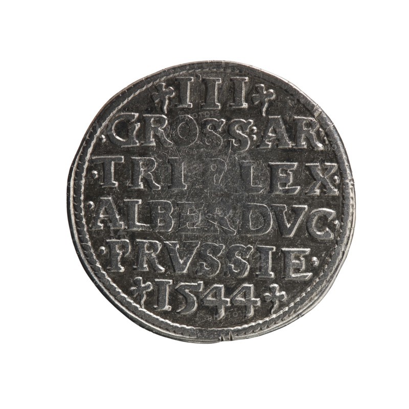 Trojak, Decius, Jost Ludwik fl. 1528–1535 co-creator, Schilling, Maciej publisher. Albrecht Hohenzollern Prince of Prussia; 1490–1568 — iconography: trefoils, male busts in armour. Obverse: male bust in armour in profile turned to the right; short hair, long beard with sideburns. In the rim an inscription beginning with a trefoil: -ALBER DG MAR BRAN DVX PRVS; pearl border; plant motifs between the words. Reverse: in the pearl border an inscription in six lines: -III-/.GROSS:AR:/.TRIPLEX./.ALBER:DVC./.PRVSSIE./-I544-; the denomination and date are between the trefoil marks. 1544. Ducal Prussia 1525–1701, Königsberg mint. Coin; diameter 21.8 mm; weight 2.58 g; axis 225°., A circular metallic object with a worn, textured surface displayed against a white background; the object is mostly gray and silver with darker gray areas from wear and shadow, showing raised and recessed detailing across its face; the edge has a patterned border and irregularities, and the surface has scratches and sma...