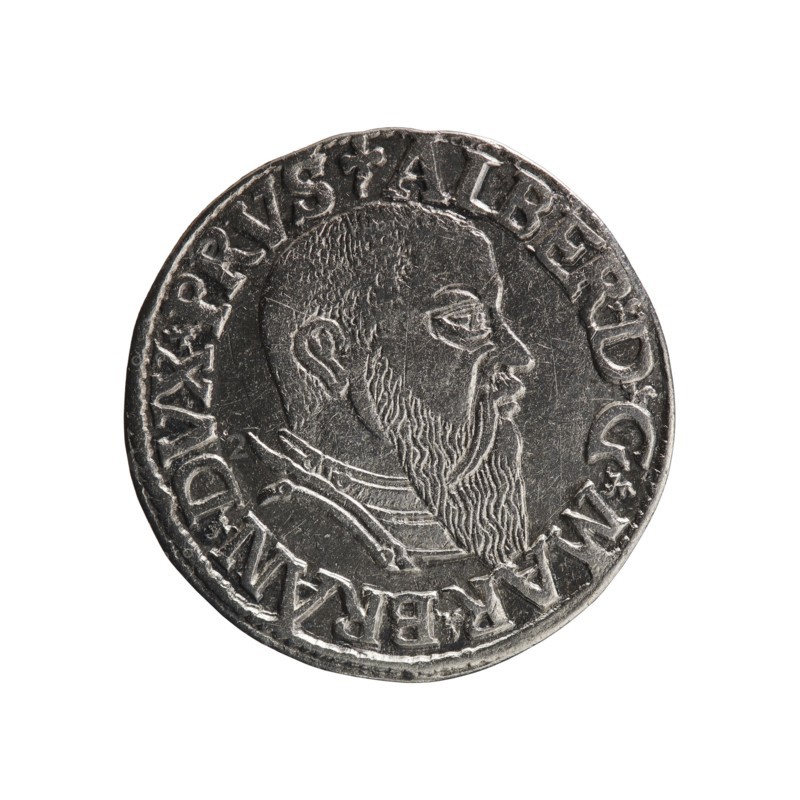 trojak, Decius, Jost Ludwik fl. 1528-1535 co-creator, Schilling, Maciej mintmaster / publisher, Albrecht Hohenzollern Prince of Prussia; 1490-1568 - iconography: trefoils, male busts in armour. Obv.: male bust in armour in profile right; short hair, long beard with sideburns. In the rim an inscription beginning with a trefoil -ALBER DG MAR BRAN DVX PRVSS; pearl border, plant motifs between the words. Rev.: in the pearl border an inscription in six lines -III-/.GROSS:AR:/.TRIPLEX./.ALBER:DVC./.PRVSSIE./-I544-; the denomination and date are between the trefoil marks. 1544. Ducal Prussia 1525–1701, Königsberg mint. Coin; diameter 21.0 mm, weight 2.50 g, axis 90°., A round metallic coin with a worn silver-gray surface showing a raised profile of a bearded man facing right; the portrait displays textured hair and a long beard with etched lines, and the shoulder area shows part of clothing with layered collars. Around the edge of the coin is a raised rim with a continuous decorative band fea...