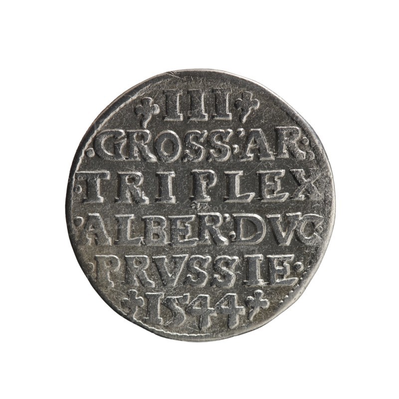 Trojak; Schilling, Maciej mintmaster; Decjusz, Jost Ludwik fl. 1528–1535 co-creator. Obverse: male bust in armour in profile turned right; short hair, long pointed beard with sideburns. Rim inscription beginning with a trefoil: -ALBER DG MAR BRAN DVX PRVSS. Pearl border; plant motifs between words. Reverse: inscription in six lines within pearl border: -III-/.GROSS:AR:/.TRIPLEX./.ALBER:DVC./.PRVSSIE./-I544-. Denomination and date between trefoil marks. Date: 1544. Place: Ducal Prussia, Königsberg. Iconography: Albrecht Hohenzollern Prince of Prussia; 1490–1568 — trefoils, male busts in armour. Coin; diameter 21.0 mm; weight 2.48 g; axis 340°., A round metal coin with a worn, textured surface shown against a white background; the coin appears silver-gray with darker gray shadows in recessed areas and lighter silvery highlights on raised portions; the face of the coin shows a group of raised, blocky characters arranged in horizontal lines and separated by shallow grooves, with small deco...