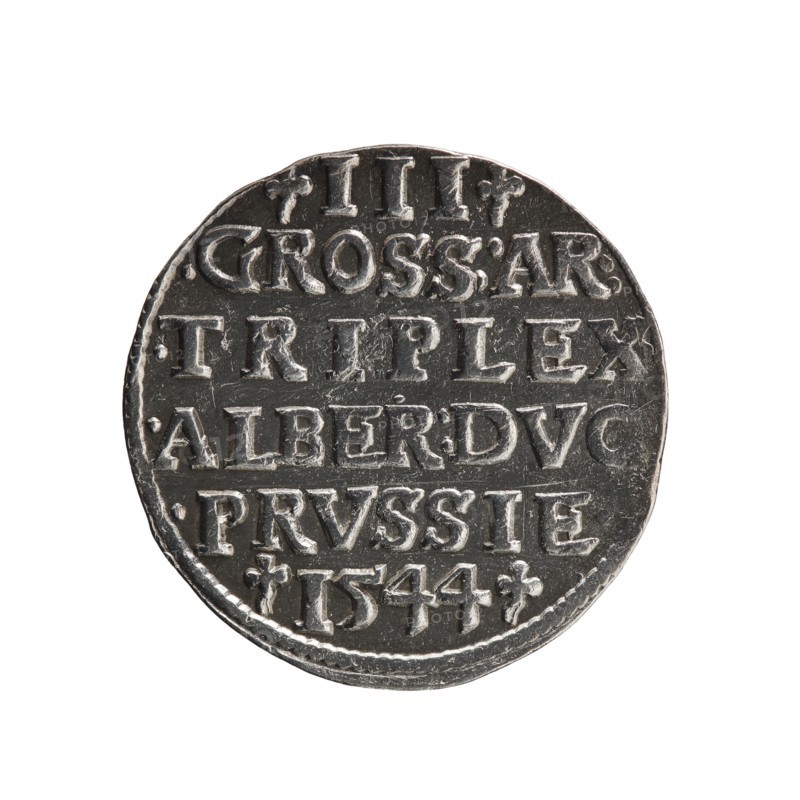 Trojak coin by Schilling, Maciej mintmaster and co-creator Decjusz, Jost Ludwik fl. 1528–1535 mint manager. Obverse: male bust in armour in profile to right; short hair, long pointed beard with sideburns; rim inscription beginning with a trefoil: -ALBER DG MAR BRAN DVX PRVS; pearl border, plant motifs between words. Reverse: six-line inscription in the pearl border: -III-/.GROSS:AR:/.TRIPLEX./.ALBER:DVC./.PRVSSIE./-I544-; denomination and date between trefoil marks. Date: 1544. Place: Ducal Prussia, Königsberg mint. Coin: diameter 21.1 mm, weight 2.62 g, axis 290°., A round coin with a metallic silver and dark gray surface, showing raised and recessed areas; the coin's edges are slightly irregular and worn, and the face displays a pattern of raised rectangular shapes and ornamental marks arranged in horizontal bands across the surface, with visible texture and small scratches.