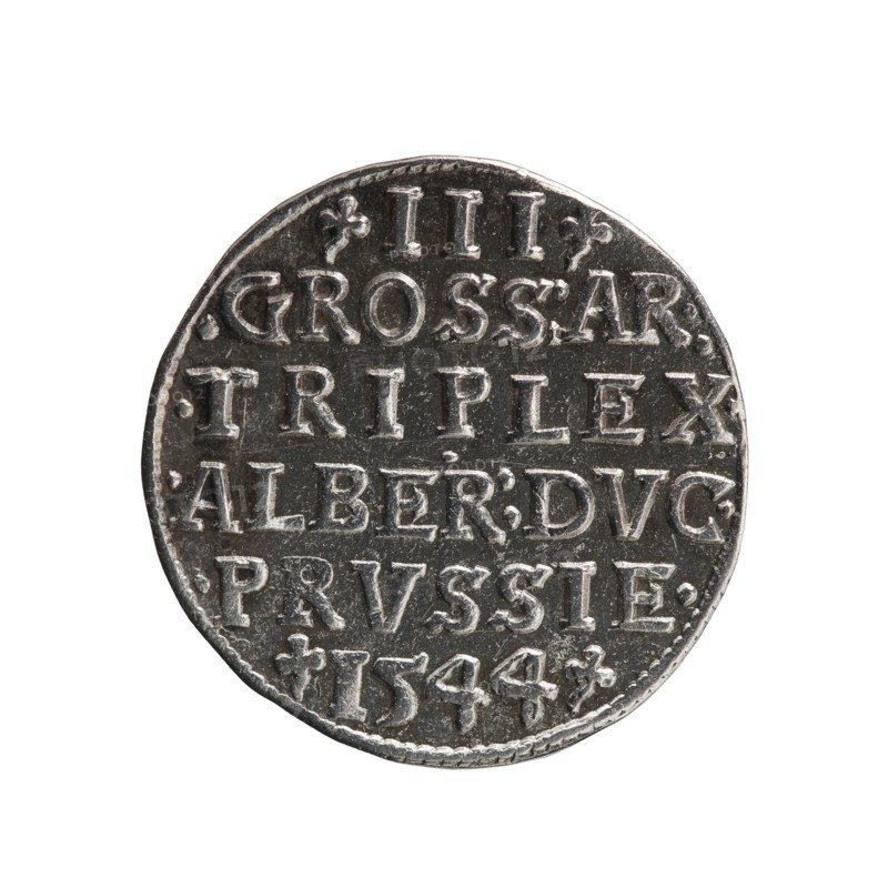 trojak, Schilling, Maciej mintmaster / publisher, Decjusz, Jost Ludwik fl. 1528-1535 co-creator; mint manager, Albrecht Hohenzollern Prince of Prussia; 1490-1568 - iconography, trefoils, male busts in armour. Obv.: male bust in armour in profile turned to the right; short hair, long pointed beard with sideburns. In the rim an inscription beginning with a trefoil: -ALBER DG MAR BRAN DVX PRVSS; pearl border, plant motifs between the words. Rev.: in the pearl border an inscription in six lines: -III-/.GROSS:AR:/.TRIPLEX./.ALBER:DVC./.PRVSSIE./-I544-; the denomination and date are between the trefoil marks. 1544. Ducal Prussia 1525–1701, Königsberg mint. Coin; diameter 21.4 mm, weight 2.62 g, axis 20°., A round metallic coin with a worn textured surface, showing raised lettering and decorative marks across its face; the coin appears primarily silver and dark gray with lighter highlights on the raised areas and darker recessed areas, and the edge shows a slightly irregular rim.