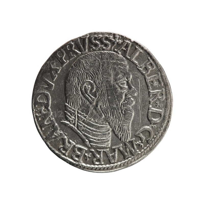 Trojak; Schilling, Maciej mintmaster; Decjusz, Jost Ludwik fl. 1528–1535 co-creator. Obverse: male bust in armour in profile to right; short hair, long pointed beard with sideburns; rim inscription beginning with a trefoil: -ALBER DG MAR BRAN DVX PRVSS; pearl border; plant motifs between words. Reverse: pearl border with six-line inscription: -III-/.GROSS:AR:/.TRIPLEX./.ALBER:DVC./.PRVSSIE./-1545-; denomination and date between trefoil marks. 1545. Ducal Prussia 1525–1701, Königsberg mint. Coin; diameter 21.2 mm; weight 2.65 g; axis 45°., A round metallic coin with a worn surface showing a raised profile of a bearded man facing right; the man has short hair and detailed facial features and is wearing a layered collar or armor, and the rim of the coin features a raised decorative border with several interrupted raised elements. The visible colors are silver and shades of gray, with darker gray in recessed areas and lighter silver on raised highlights.