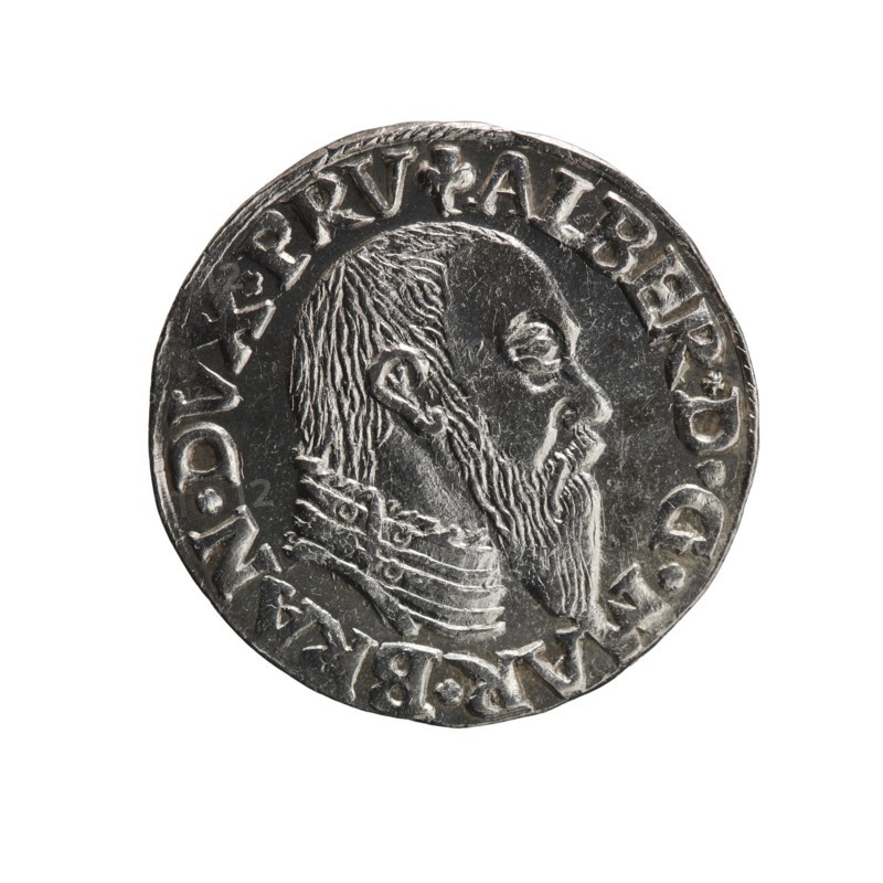trojak, Schilling, Maciej mintmaster; co-creator. Obverse: male bust in armour in profile turned to the right; short hair, long pointed beard with sideburns; in the rim an inscription beginning with a trefoil -ALBER*D*G*MAR*BRAN*DVX*PRV; pearl border. Reverse: in the continuous border an inscription in six lines -III-/.GROSS:AR:/.TRIPLEX./.ALBER:DVC./.PRVSSIE./-I546-; the denomination and date are between trefoil marks. 1546. Ducal Prussia 1525–1701, Königsberg mint. Coin; diameter 21.2 mm; weight 2.66 g; axis 200°., A round metallic coin shown against a white background, with a raised profile of a bearded man facing right, visible hair and beard texture and a detailed collar or garment at the neck; the coin surface is mostly silver-gray with darker gray recessed areas and lighter highlights on raised details, and a decorative raised rim surrounding the portrait.