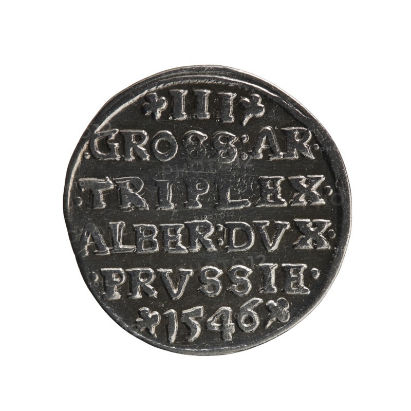 trojak, Schilling, Maciej mintmaster; co-creator; Albrecht Hohenzollern Prince of Prussia; 1490–1568 — iconography: trefoils, male busts in armour. Obv.: male bust in armour in profile facing right; short hair, long pointed beard with sideburns. In the rim an inscription beginning with a trefoil: -ALBER*D*G*MAR*BRAN*DVX*PRVS; pearl border. Rev.: continuous border inscription in six lines: -III-/.GROSS:AR:/.TRIPLEX./.ALBER:DVC./.PRVSSIE./-I546-; denomination and date between trefoil marks. 1546. Ducal Prussia 1525–1701, Königsberg; coin. Diameter 21.9 mm, weight 2.51 g, axis 270°., A round metallic object with a reflective silver-gray surface showing raised, carved lettering arranged in several horizontal lines, set against a plain white background; the metal has darker recessed areas creating contrast and slight scratches and wear visible on the surface, and the overall colors visible are silver-gray, dark gray, and white.