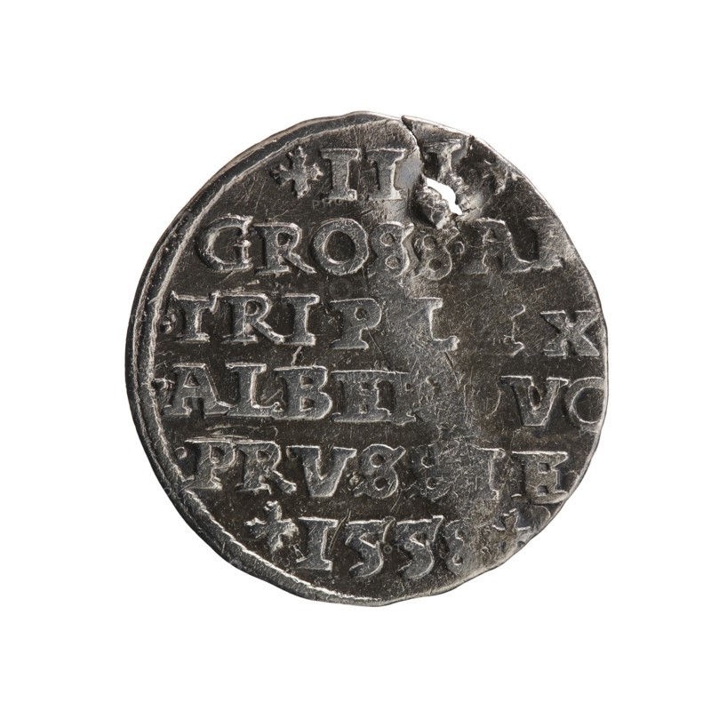 trojak, towers, Albrecht Hohenzollern Prince of Prussia; 1490–1568 - iconography, male busts in armor. Obverse: male bust in armor in profile turned to the right; short hair, long pointed beard with sideburns. In the rim an inscription beginning with a tower: -ALBER.DGMAR.BRAN.DVX.PRVSS; continuous border. Reverse: in the pearl border an inscription in six lines: +III+/GROSS.AR/.TRIPLEX/.ALBER DVC /.PRVSSIE./+I558+. Denomination and date between lilac crosses, 1558. Ducal Prussia 1525–1701, Königsberg; coin. Diameter 21.3 mm, weight 2.42 g, axis 0°., A round metal coin with a worn and uneven surface, showing a few dents and a small hole near the edge; the coin appears primarily silver-gray with darker gray areas in the recessed parts and lighter silver highlights on raised surfaces; a group of incised shapes and carved details form rows across the face but no text should be described; the coin edge is slightly irregular and the background is plain white.