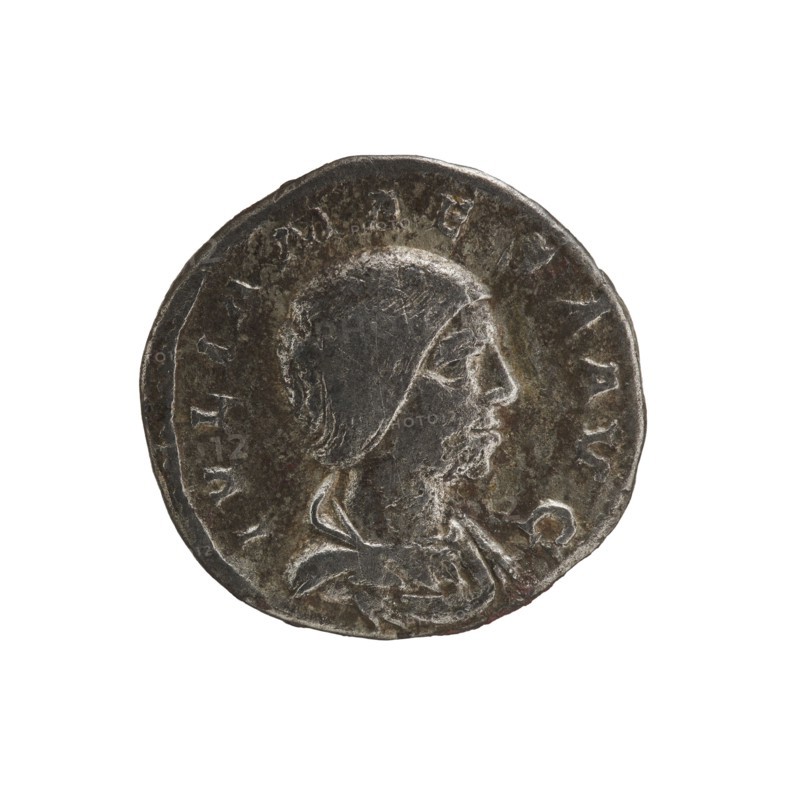 Denarius, Elagabalus 204–222; Roman emperor 218–222. Obv.: IVLIA MAESA AVG — Draped bust of Julia Maesa facing right, pearl border. Rev.: PVDICITIA — Pudicitia with a veil on her head seated on a throne facing left, lifting the hem of her veil with her right hand and holding a scepter in her left, pearl border. Rome, 218–223. Coin; diameter 19.5 mm; weight 3.50 g., A round metallic object with a worn, dark gray surface and lighter gray highlights showing a raised profile of a person wearing a close-fitting head covering and a draped garment, set against a plain white background; the object shows uneven edges, surface scratches, and areas of lighter silvery sheen along the raised features and rim.