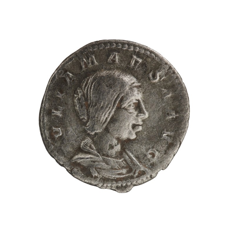 Denarius, Julia Maesa ca. 160–224; Augusta 218–224. Obverse: IVLIA MAESA AVG — draped bust of Julia Maesa facing right, pearl border. Reverse: PVDICITIA — veiled Pudicitia seated on a throne facing left, raising the hem of her veil with her right hand, holding a scepter in her left, pearl border. Roman Empire, 218–223, Rome. Coin; diameter ~18.5–19.0 mm; weight 3.05 g., A round metallic coin with a worn surface showing a raised profile of a person facing right, with visible facial features and hair pulled back beneath a draped head covering; the coin has a beaded rim and decorative raised edges, with textured areas of wear and small dents around the perimeter. The visible colors are shades of gray, silver, and dark gray with small brownish spots.