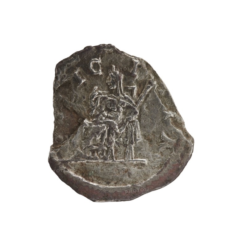 Denarius of Elagabalus 204–222; Roman emperor 218–222. Obverse: IVLIAMAESAAVG — Draped bust of Julia Maesa facing right, pearl border. Reverse: PVDIC ITIA — Veiled Pudicitia seated on a throne facing left, raising the hem of her veil with her right hand and holding a scepter in her left, pearl border. Date: 218–223. Place of origin: Rome, Roman Empire 27 BC–476. Object: coin denarius, diameter ca. 17.0–18.5 mm, weight 1.85 g., A worn, irregularly shaped metal object with a rough, pitted surface showing a carved scene in low relief; the carving depicts a seated figure next to another standing figure with elongated, angular limbs and draped clothing, both set on a slightly raised base line. The object displays a range of muted colors including dark gray, brown, and hints of greenish and reddish tones, with lighter silvery highlights along raised edges and carved lines. The edges are uneven and chipped, and the surface shows scratches and areas of smoother wear. The background around the ...