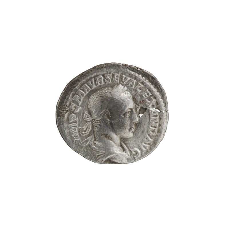 Denarius; personifications; Alexander Severus Roman emperor, 222–235 — iconography: Salus. Obverse: IMPCMAVRSEVALEXANDAVG — Bust of Alexander Severus with laurel wreath and paludamentum facing right, pearl rim. Reverse: SALVSP VBLICA — Salus seated facing left, holding a patera in her right hand feeding a snake coiled around an altar, left hand on the backrest, pearl rim. Date: 222–228. Roman Empire. Rome. Coin. Diameter 17.5–20.0 mm. Weight 2.38 g., A circular metallic object with a worn, uneven surface showing a raised profile of a person facing right, including facial features, ear, and stylized hair tied at the back; the rim has raised decorative elements and a noticeable crack near the right edge; visible colors include silver, gray, and darker gray areas from wear and patina.