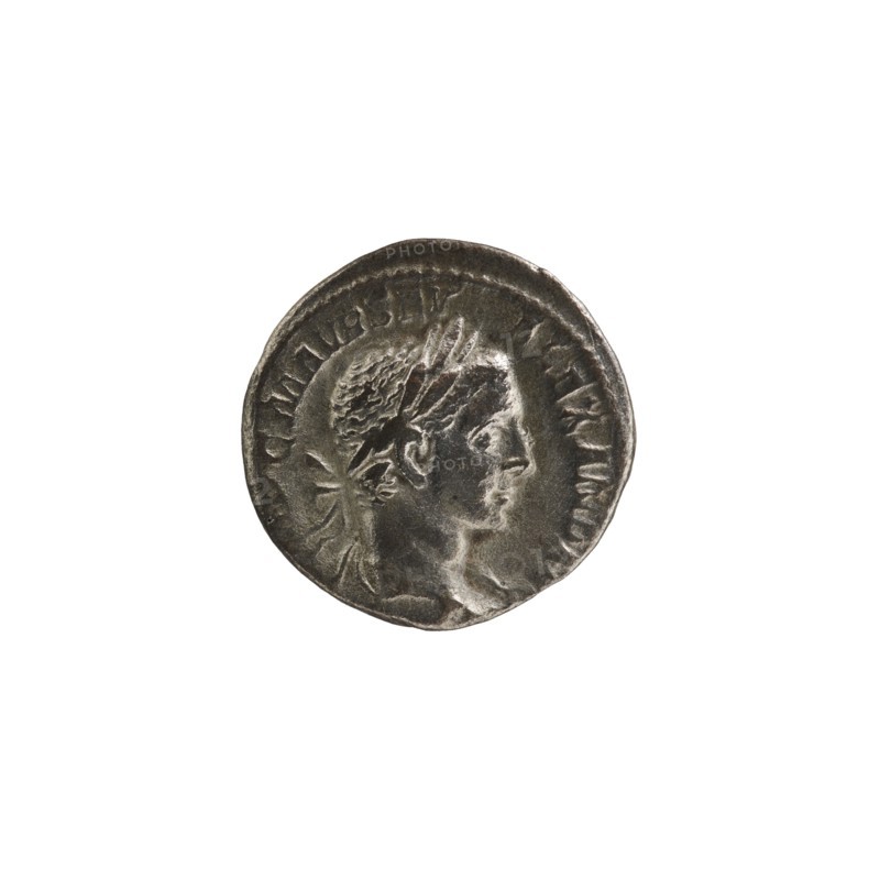 Denarius; Roman; Alexander Severus emperor, 222–235. Obverse: Bust of Alexander Severus right, laurel wreath and paludamentum; legend IMPCMAVRSEVALEXANDAVG. Reverse: Jupiter half-naked seated on throne facing left, holding Victoria in his outstretched right hand and a spear in his left; legend IOVI VL TORI. Pearl rim. Date: 222–228. Material: coin. Diameter: 17.0–18.0 mm. Weight: 2.90 g., A circular metallic coin with a weathered surface showing a raised profile of a person's head facing right, wearing a laurel or wreath-like headpiece; the coin's rim is slightly irregular and the surface has areas of darker and lighter metallic gray tones with a subtle reflective sheen.