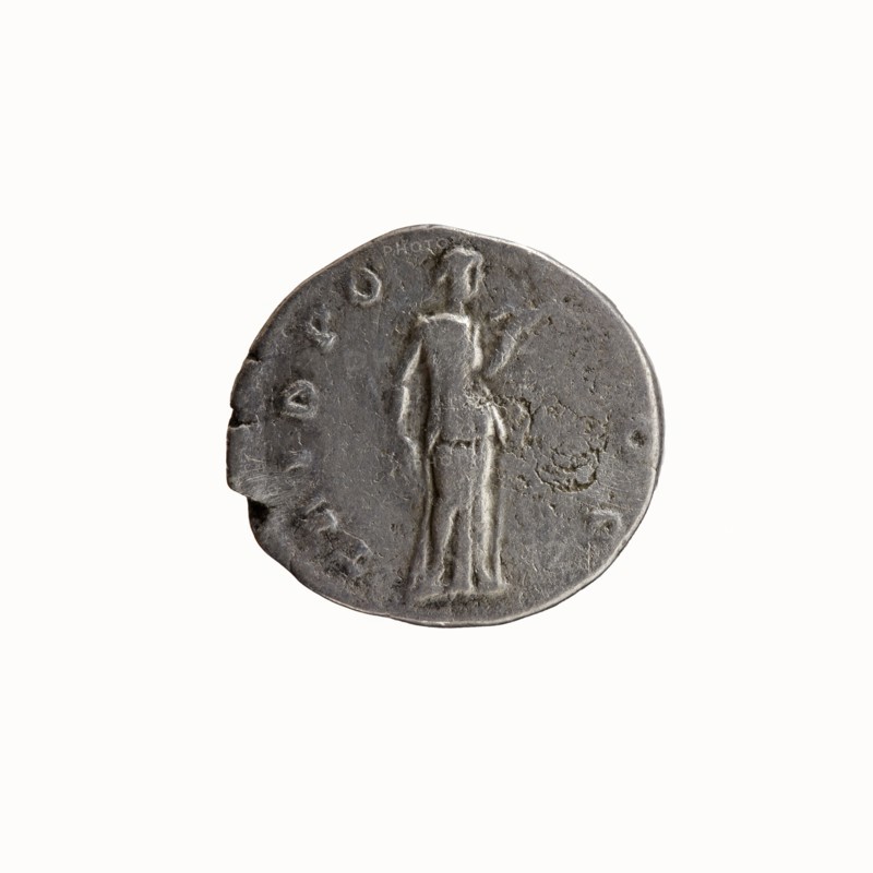 Denarius, 138. Obverse: Head of Antoninus Pius without a cap to the right; inscription IMP T AEL CAES - ANTONINVS around. Reverse: Diana stands to the right, holding a bow in her outstretched left hand and a lowered arrow in her right; inscription TRIB PO - T COS around. Issuer: Hadrian; Caesar: Antoninus Pius as caesar 138. Iconography: Diana; attributes: bows, arrows; Roman deities. Roman Empire, Rome. Coin: diameter 16.5–18.0 mm, weight 2.88 g, axis 195°., A round, worn coin with a metallic gray surface shows a raised, stylized standing human figure in profile, facing to the right, with simple, elongated limbs and draped clothing; the coin’s edges are slightly irregular and chipped in places, and the surface has a textured, pitted appearance with darker and lighter gray variations.