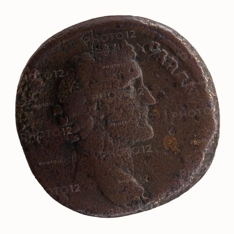 Sestertius, Hadrian 76–138; Roman emperor 117–138 as issuer; Antoninus Pius 86–161; Roman emperor 138–161, caesar 138 — personifications; sacrifice; Pietas standing before an altar; altars. Obverse: Head of Antoninus Pius bare, facing right, legend IMP T AELIVS CAE - SAR ANTONINVS. Reverse: Pietas stands left before an altar, making an offering with his right hand and holding a container of perfumes in his left, legend TRIB POT COS DES II, episode PIETAS. Date: 138. Place of origin: Rome, Roman Empire. Object: coin sestertius. Diameter: 29.5–30.0 mm. Weight: 26.32 g. Axis: 180°., A round, worn metal coin with a raised profile of a person facing right; the surface shows rough, pitted texture and areas of corrosion. The coin displays dark brown and reddish-brown tones with patches of lighter brown and small spots of yellowish-orange. The rim is uneven and slightly raised in places, and the details of the portrait and surrounding area are smoothed and partially obscured.