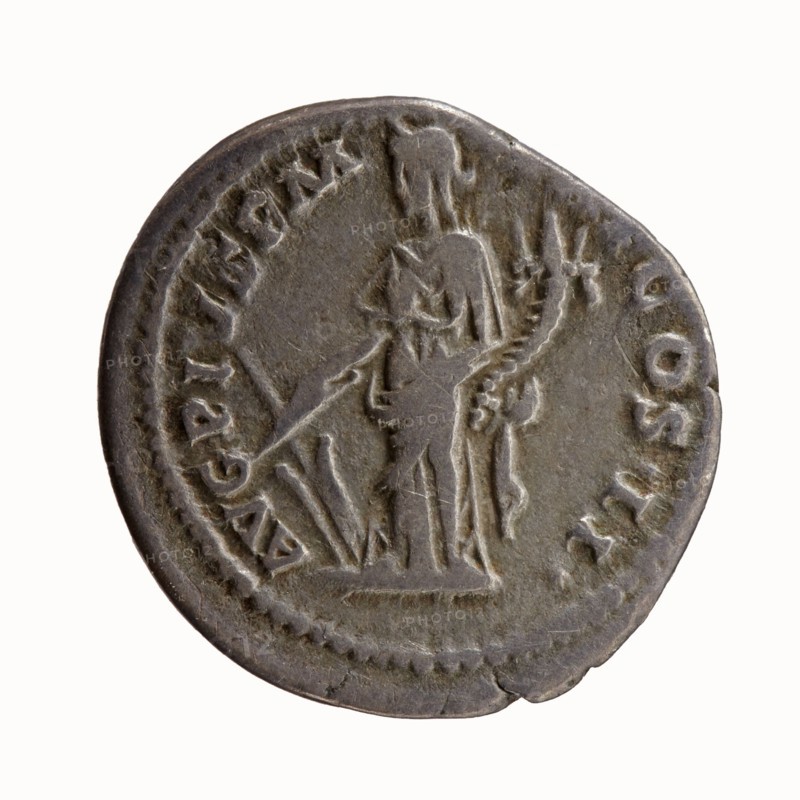 Denarius of Antoninus Pius 86–161; Roman emperor 138–161. Obverse: bare head of Antoninus Pius right, legend IMP T AEL CAES HADR - ANTONINVS. Reverse: Fortuna standing left, holding a rudder in her right hand and a cornucopia in her left, legend AVG PIVS PM - TR P COS II. Date: 139. Rome, Roman Empire. Bronze/silver coin; diameter ~17.5–18.0 mm, weight 3.52 g, axis 180°., A circular metallic coin with a worn, uneven edge and a greyish-brown patina shows a raised relief of a standing human figure in profile, draped in a long garment and holding a long staff or spear; the figure faces left and has details of hair or a headpiece and what appears to be drapery folds and a curved object beside the body. The coin surface includes a dotted border around the rim and several raised areas of texture and wear; visible colors are grey, brown, and hints of darker grey.