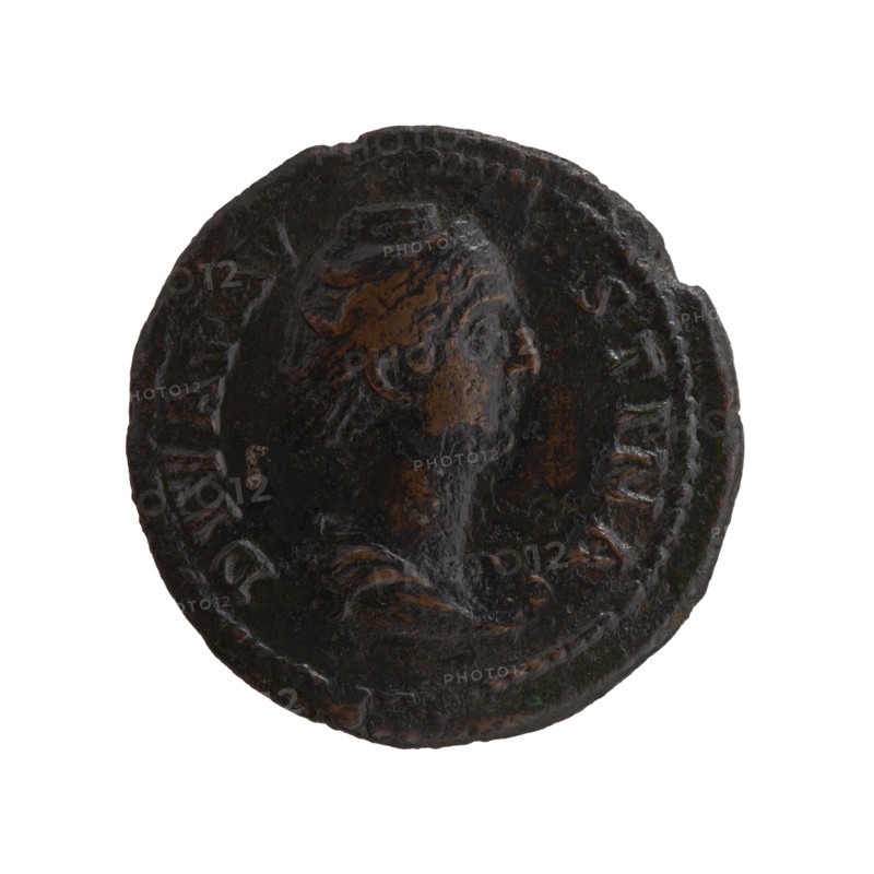 Dupondius/as; bust of Faustina the Elder 98–141; Roman empress 138–141 in drapery facing right; inscription DIVA FAV•STINA around; reverse: Ceres standing right, holding a long torch in her right hand and ears of corn in her lowered left hand; inscription A VG•VST•A all around in SC. fields; posthumous issue of Antoninus Pius 86–161; Roman emperor 138–161, Roman Empire, after 141; bronze coin; diameter 27.0–27.5 mm; weight 9.90 g; axis 180°., A round, worn coin with a raised profile of a head facing right in the center, showing textured hair and facial features; the coin surface is uneven and pitted with areas of darker and lighter wear. The coin displays a mix of dark brown and black tones with patches of lighter brown where the raised details catch light, and small hints of green oxidation in a few spots. The rim is irregular and shows a beaded border around much of the edge, and the overall appearance is aged and corroded.