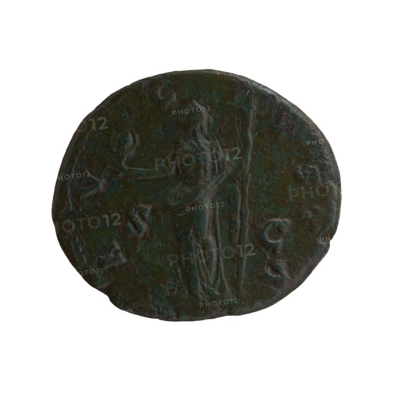 Dupondius/as, Faustina the Elder 98–141; Roman empress 138–141 posthumous, Antoninus Pius 86–161; Roman emperor 138–161 issuer. Bust of Faustina I in drapery facing right, inscription DIVA · FAVSTINA all around; reverse: Vesta standing left, holding a statuette of Athena palladium in her outstretched right hand, and a long torch in her left, inscription A · V · G · VSTA all around, in SC. Fields. After 141. Roman Empire. Bronze coin; diameters: 24.5 mm and 28.5 mm; weight 10.90 g; axis 195°., A round, dark greenish-brown coin with a worn, textured surface showing a standing human figure in relief near the center; the figure appears draped and holds a long vertical object beside them while extending an arm toward a small raised element to the left. The coin edge is uneven and slightly irregular, and the overall coloration includes tones of dark green, brown, and hints of black with lighter green highlights on raised areas.