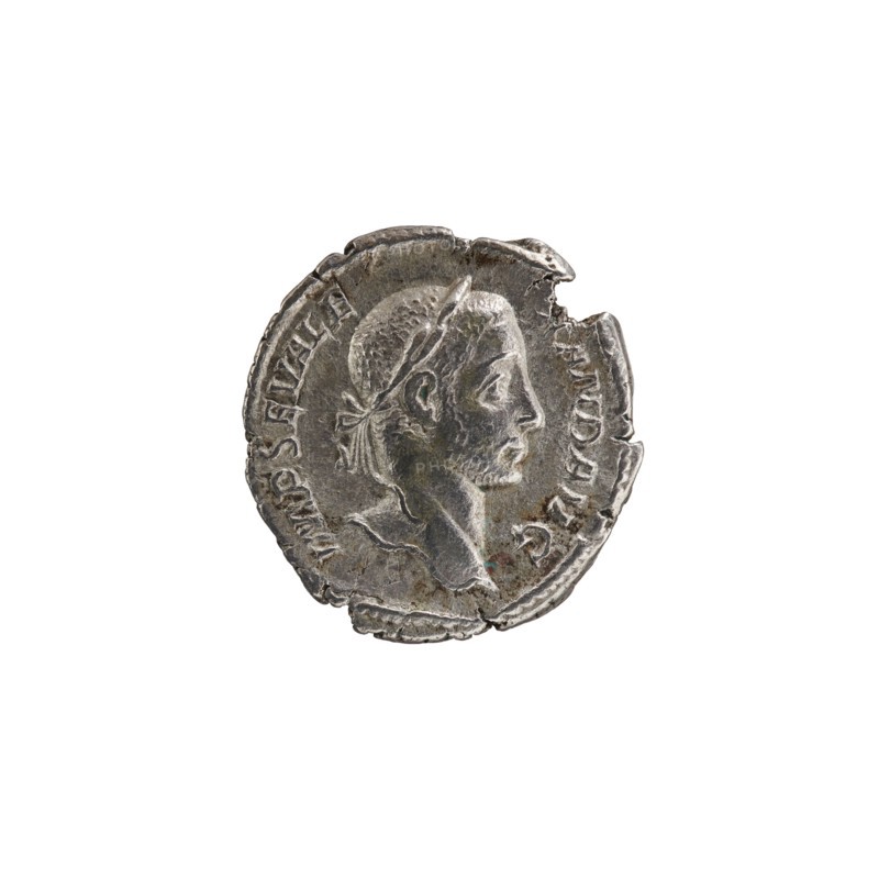 Denarius of Alexander Severus emperor 222–235 CE, 229 CE, Rome. Obverse: portrait of Alexander Severus iconography, ruler. Reverse: personification Libertas. Roman Empire 27 BCE–476 CE. Coin; diameter approx. 18.5–19.0 mm; weight 2.65 g., A worn round metallic object with an irregular edge showing chips and indentations, featuring a raised profile of a person's head facing right with short textured hair and a headband, a visible neck and shoulder, and faint raised decorative elements around the rim; dominant colors are silver and gray with small areas of darker tarnish and subtle greenish spots.
