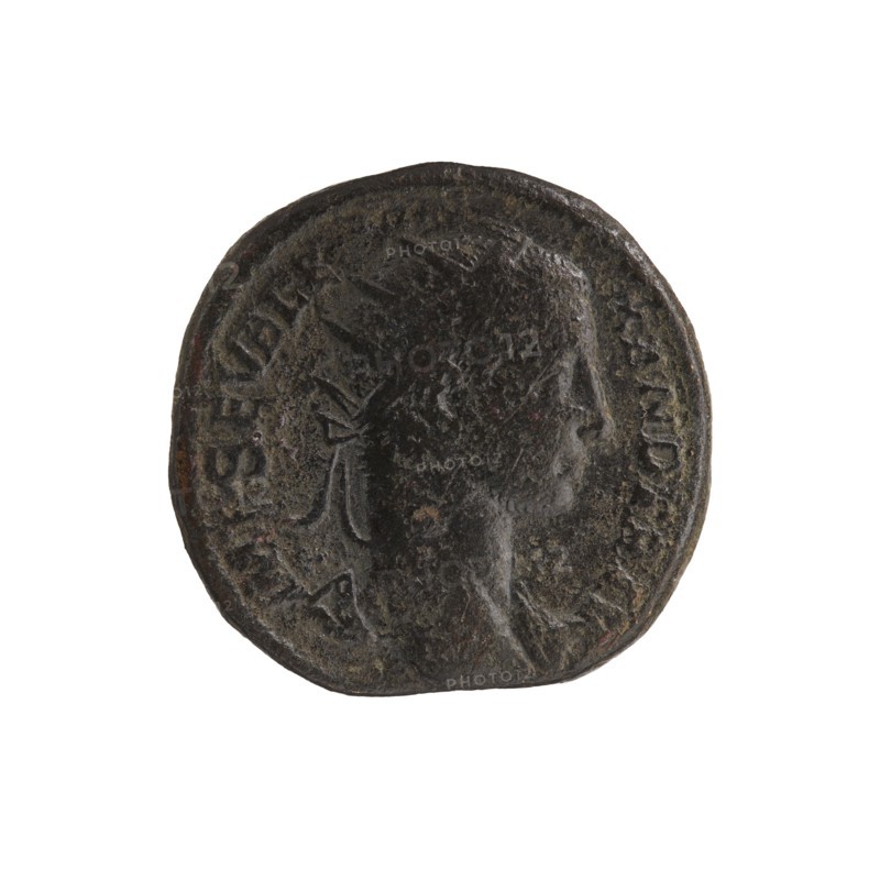 Dupondius; quadriga; Alexander Severus Roman emperor, 222–235 — iconography: emperor on quadriga; dated 229; Roman Empire 27 BC–476, Rome mint; coin; diameter 24.5–25.0 mm; weight 13.71 g, A round, worn dark brown to black coin with uneven edges, showing the raised profile of a person's head in three-quarter view, with visible hair and what appears to be a tied ribbon or band at the back of the head; the coin surface has areas of lighter brown and greenish patina, textured pitting, and a raised rim encircling the portrait.