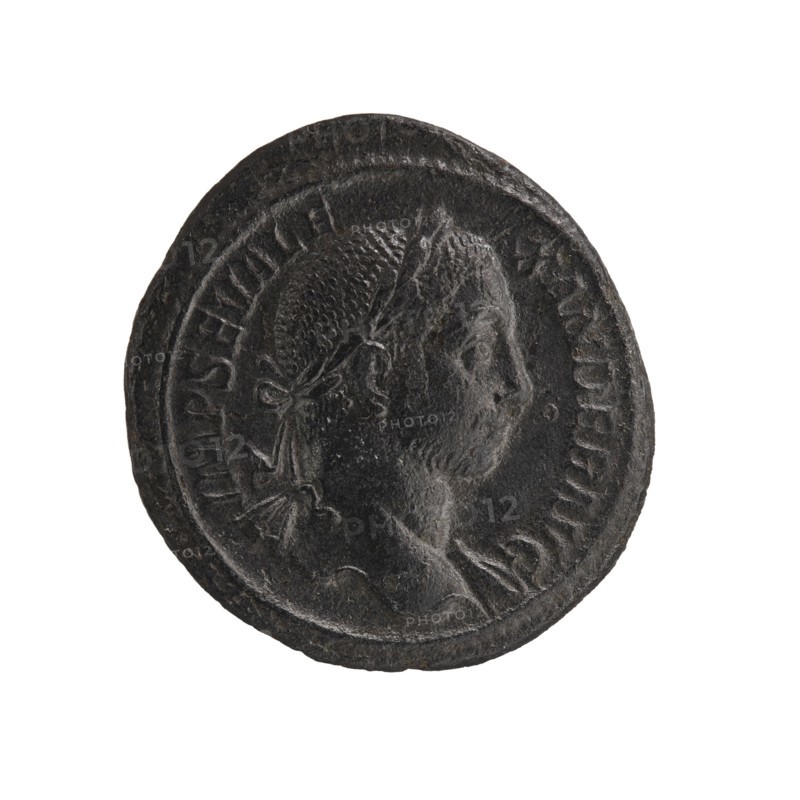 Personifications; Libertas personification; Alexander Severus Roman emperor; 222–235 — iconography; Roman Empire 27 BC–476; Rome; coin; diameter 26.0 mm; diameter 28.0 mm; weight 11.73 g, A dark, round coin with a raised rim occupies the center of the image against a white background; the coin appears mostly black and dark gray with textured, worn surfaces, and shows a right-facing bust of a person with short, textured hair and a tied ribbon or band at the back of the head, along with a suggestion of shoulders and drapery below the neck.