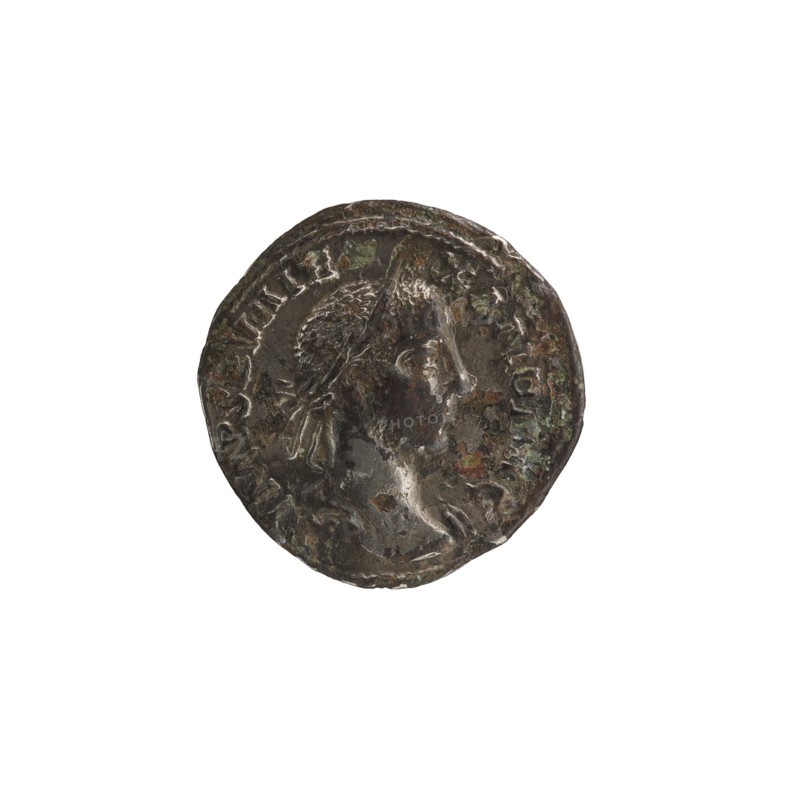 Denarius depicting Roman deities and Jupiter; Alexander Severus Roman emperor, 222–235 — iconography, 228–231. Roman Empire, Rome. Coin; diameter 19.0 mm; weight 2.27 g., A round, worn metallic object centered on a white background, showing a raised profile of a human head in relief facing right and surrounded by a decorative border; the surface has irregular pits and areas of corrosion with varied tones. The visible colors include dark gray, brown, greenish patina, and hints of lighter silvery highlights.