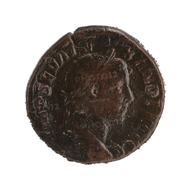 sestertius; personifications; Alexander Severus Roman emperor; 222–235 — iconography: Annona personification; date: 228–231; Roman Empire 27 BC–476 place of origin: Rome; object type: coin sestertius; dimensions: diameter 28.0–28.5 mm; weight 18.01 g, A circular metallic object with a dark brown and black patina, showing the raised profile of a person's head in relief facing right; the head has short hair and a laurel-like band, and the surface shows worn and shiny areas with uneven texture and small chips along the rim.
