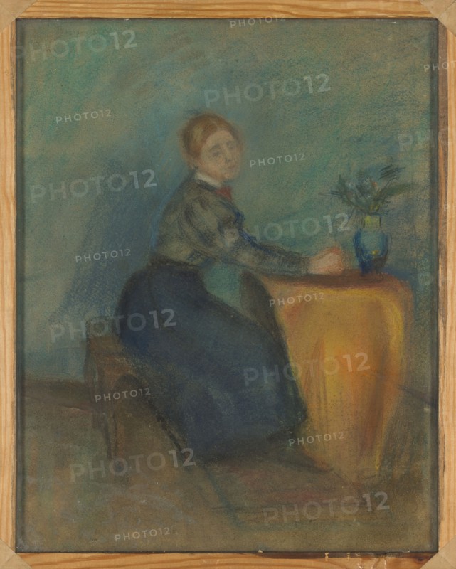 Portrait of a Girl Sitting at a Table, Olga Boznanska 1865–1940, painter; genre scene, Young Poland; Poland; women; Polish painting; ca. 1892; pastel drawing; 45 x 36 cm., A seated woman wearing a dark skirt and a lighter top sits at a draped table covered with a warm yellow-orange cloth, her arms resting on the table near a blue vase that holds a small arrangement of foliage; the background is muted with hazy shades of blue and green, the floor and bench beneath her appear in subdued brown and gray tones, and the painting is shown within a light wooden frame.