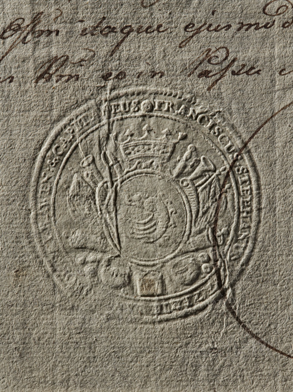 Seal of Franciszek Stefan Lanckoronski of Brzezie, Starost of Rawa Mazowiecka, Franciszek Stefan Lanckoronski (1754–1789); round seal impression, Zadora coat of arms; illegible impression, 1779, Poland; document/private/starost's seal., The image shows a close-up of textured beige paper with an embossed circular seal featuring a crowned crest and decorative elements; there is dark brown ink handwriting partially visible near the top and crossing over the seal, and a curved dark brown line extending from the right side. The visible colors are beige, various shades of brown, and a hint of gray in the paper texture.
