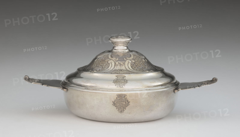 Écuelle by Louis I Dulaurier, goldsmith; tableware element. Body in the form of a smooth, circular bowl with two horizontal handles ending in shells. The arched cover is decorated with racailles and a grid, with a handle bearing a relief male bust wearing a laurel wreath. Engraved on both parts is a coat of arms under a count's crown (three-field: right, a tower on a rock on an azure field; left, two bulls on a gold field; above, three stars on a blue field). Dated 1690, 1760–1761. Toulouse. Vessel: height 13 cm, width 28.8 cm, depth 17.2 cm.